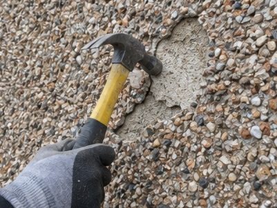 A wall being tapped to find the hollow areas of pebbledash