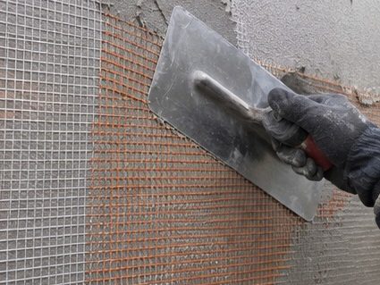 Reinforcing mesh being bedded into the base coat