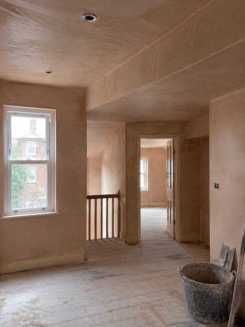 A trowel laying a finish coat across a wall