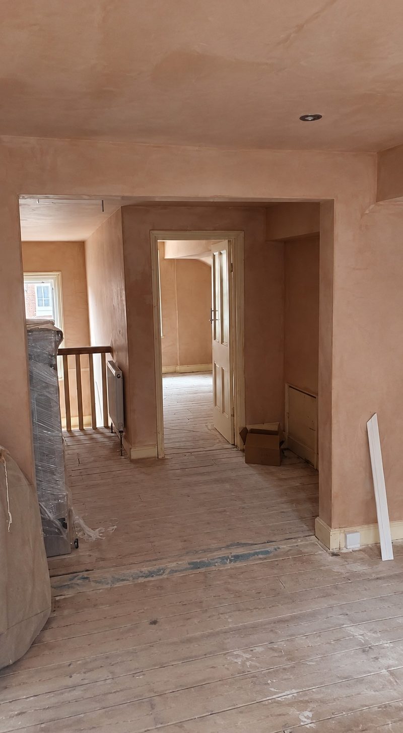 A plasterer skimming a wall in a bay fronted living room
